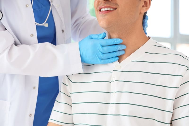 A smiling thyroid patient undergoes an exam.