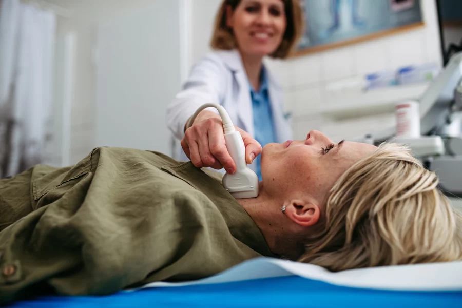 A doctor smiles while performing an ultrasound following successful RFA treatment for thyroid.
